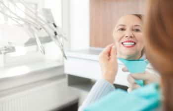 middle-aged woman looking at her teeth in the mirror